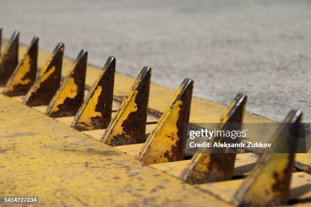 a barrier with spikes on the road to control the direction of movement, a barrier for cars. yellow unidirectional and mechanical spike strip or barrier. road spikes for an emergency traffic stop, an obstacle. - spiked stock photos et images de collection