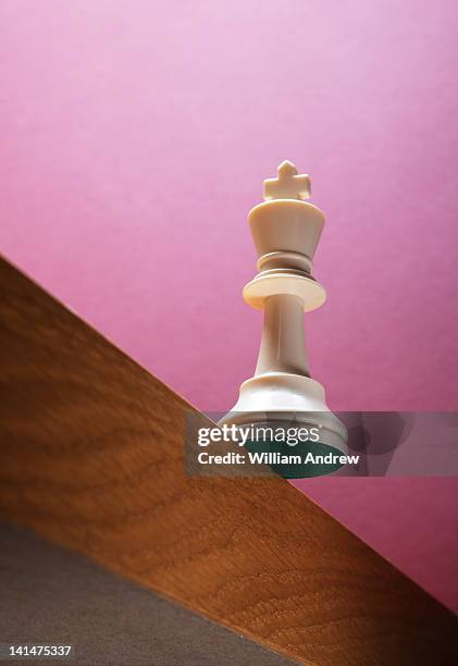 king chess piece at risk for falling of edge - king chess piece stock pictures, royalty-free photos & images