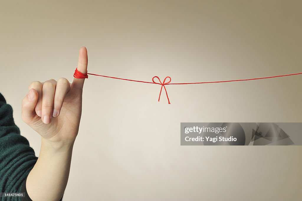 The hand of the woman connected with a red thread