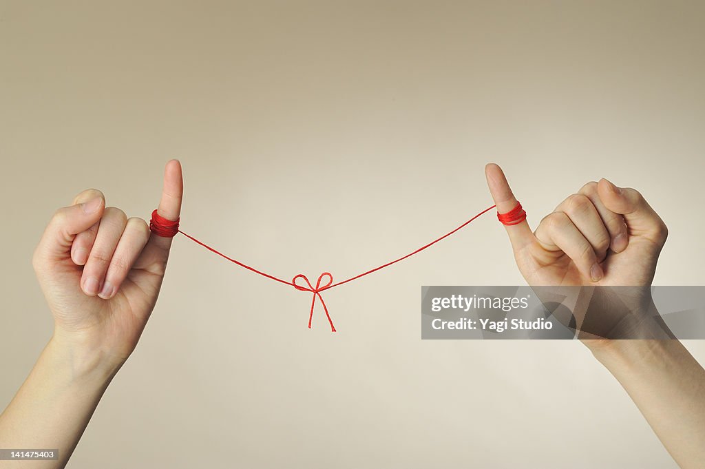 The hand of the man and woman connected with a red