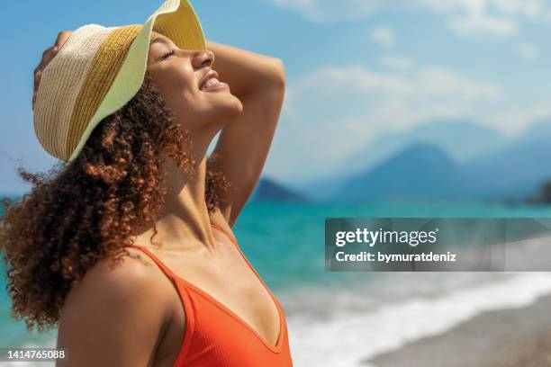 mujer joven relajante en la playa - sombrero de sol fotografías e imágenes de stock