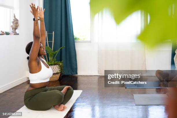 side view yoga instructor seated with arms raised - yoga instructor stock pictures, royalty-free photos & images