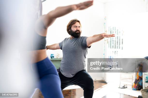 homme gay avec barbe dans la pose guerrière dans un cours de yoga - mannequin grande taille photos et images de collection