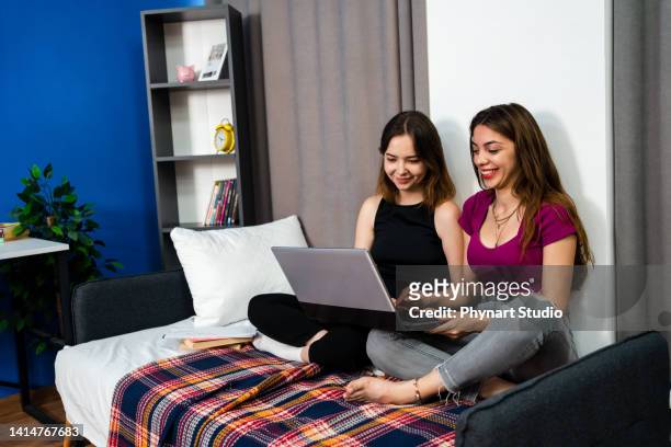 glückliche mädchen freunde geschwister mit laptop-computer schauen online-tv-show video sitzen auf dem sofa zusammen - girls television show stock-fotos und bilder
