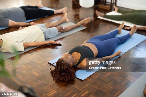 yoga students lying in shavasana - savasana stock pictures, royalty-free photos & images