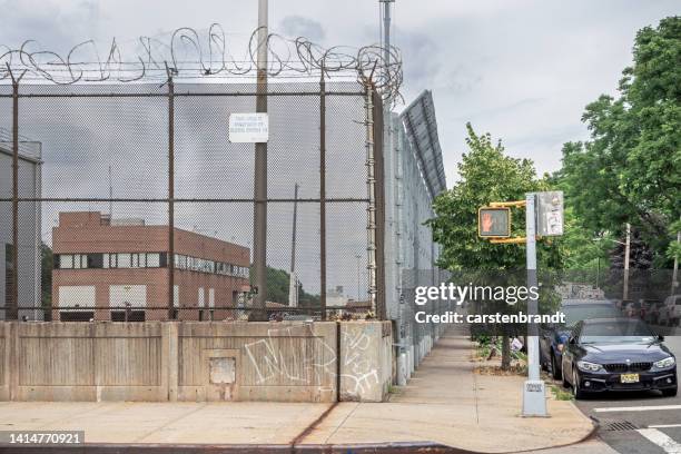 high and strong fence with barbed wire on top - mens en machine stockfoto's en -beelden