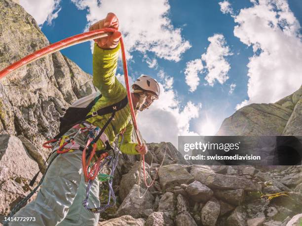 l'arrampicatatrice prepara l'attrezzatura per salire sulla parete rocciosa - messa in sicurezza foto e immagini stock