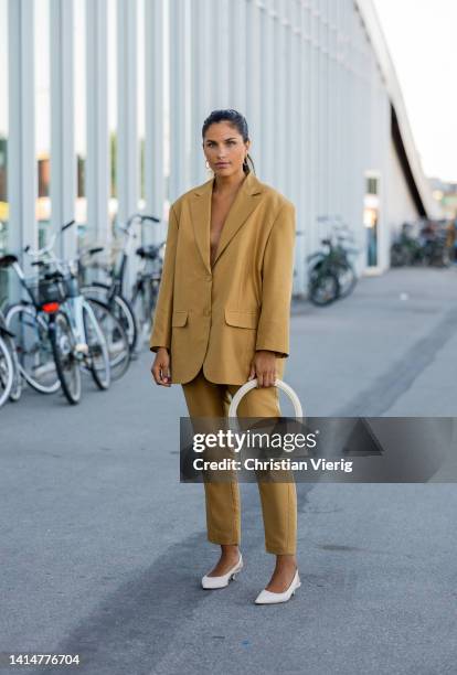 Guest is seen wearing beige oversized blazer, pants, Jacquemus bag outside Munthe during Copenhagen Fashion Week Spring/Summer 2023 on August 11,...