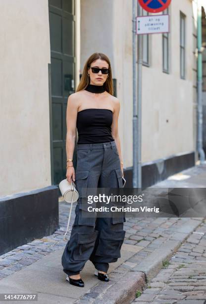Annabel Rosendahl wearing grey pants with side pockets, black cropped top, white bag outside Mark Kenly Domino Tan during Copenhagen Fashion Week...