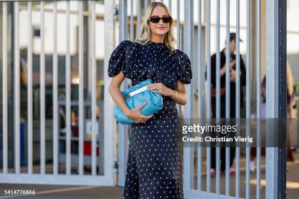 Guest seen wearing navy polka dot dress, blue bag, white sandals outside Munthe during Copenhagen Fashion Week Spring/Summer 2023 on August 11, 2022...