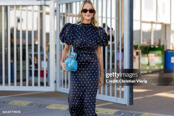 Guest seen wearing navy polka dot dress, blue bag, white sandals outside Munthe during Copenhagen Fashion Week Spring/Summer 2023 on August 11, 2022...