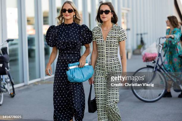 Guests seen wearing navy polka dot dress and guest wearing overall outside Munthe during Copenhagen Fashion Week Spring/Summer 2023 on August 11,...