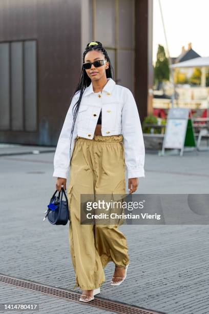 Guest is seen wearing beige pants, white cropped jacket outside Ganni during Copenhagen Fashion Week Spring/Summer 2023 on August 11, 2022 in...