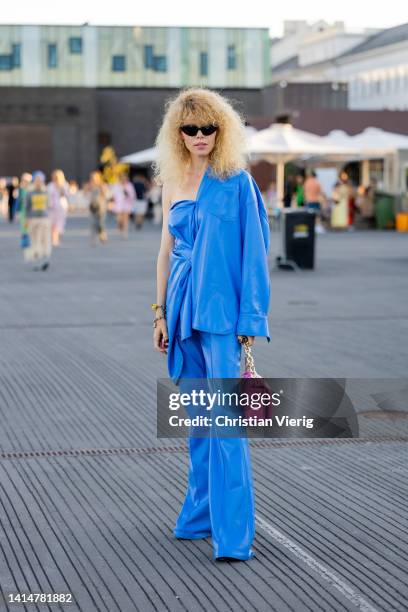 Guest is seen wearing blue blazer, top, pants, pink bag outside Ganni during Copenhagen Fashion Week Spring/Summer 2023 on August 11, 2022 in...