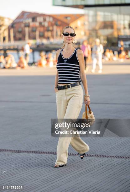 Pernille Teisbaek seen wearing black white striped Chanel top, earrings, beige pants, net bag outside Ganni during Copenhagen Fashion Week...