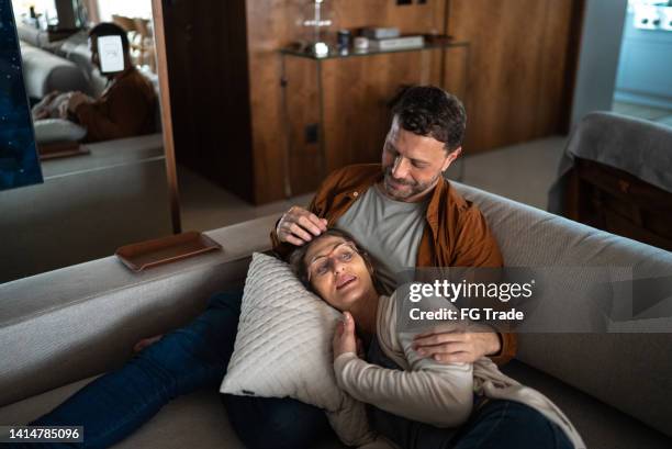 mature couple talking on the couch at home - tired couple stock pictures, royalty-free photos & images