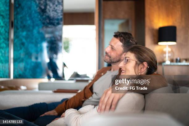 mature couple watching tv at home - live streaming stock pictures, royalty-free photos & images
