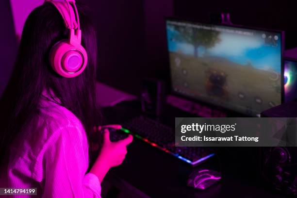 young woman smiling and talking during a live stream on a smartphone with a ring light. happy female gamer playing a video game in her computer with neon led lights - woman headphones sport smile iphone stock pictures, royalty-free photos & images