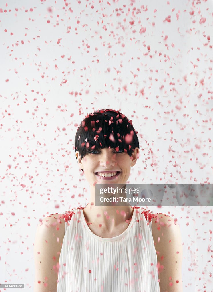 Woman smiling with red confetti falling on head