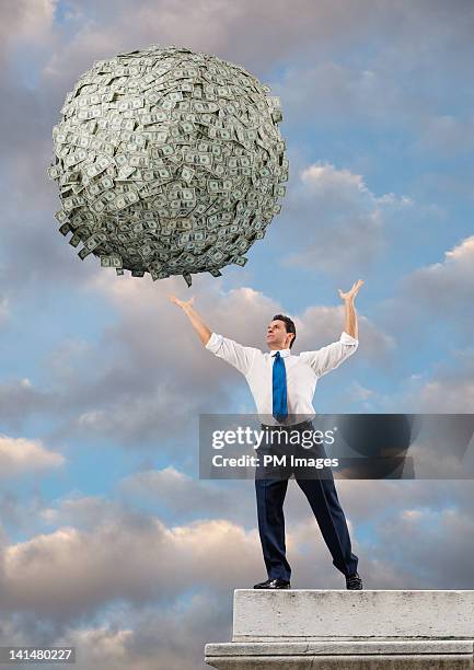 reaching for big ball of money - man with big balls stock pictures, royalty-free photos & images