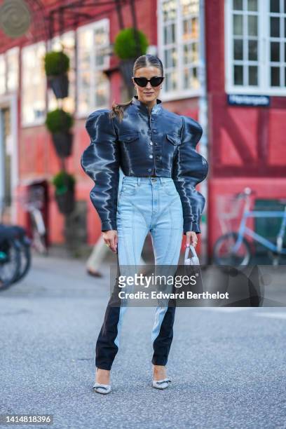 Guest wears black cat eyes sunglasses, gold earrings, a black and dray tie and dye print pattern puffy shoulder / cropped shirt, blue faded and black...