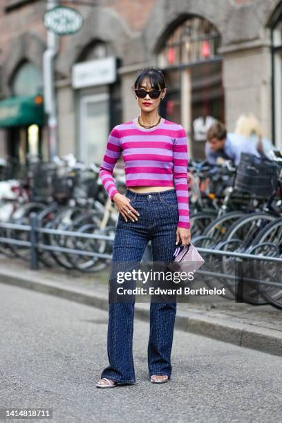 Pornwika Spiecker wears black sunglasses, black earrings, a black large chain necklace from Dior ,a purple and pink striped print pattern long...