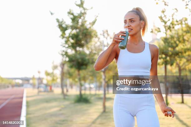 woman drinking vegetable smoothie after fitness running workout - green drink stock pictures, royalty-free photos & images