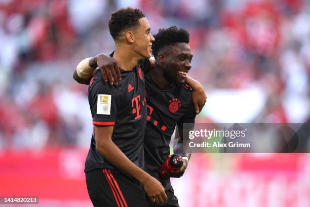 Jamal Musiala and Alphonso Davies of Bayern Munich celebrate their sides victory after the Bundesliga match between FC Bayern München and VfL...