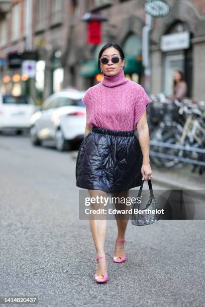 Miki Cheung wears purple sunglasses, rhinestones logo earrings from Miu Miu, a purple braided wool turtleneck / short sleeves pullover, black quilted...