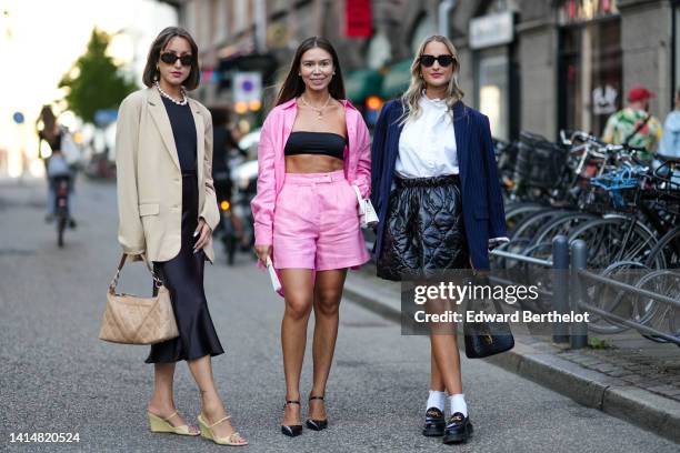 Guest wears black sunglasses, a white pearls necklace, a black t-shirt, a black satin midi skirt, a beige oversized blazer jacket, a beige quilted...