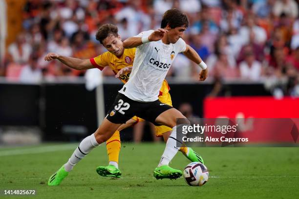 Jesus Vazquez of Valencia CF is challenged by Rodrigo Riquelme of Girona FC during the LaLiga Santander match between Valencia CF and Girona FC at...