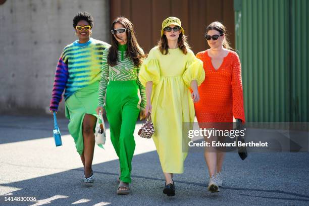 Guest wears yellow sunglasses, gold earrings, gold chain pendants necklaces, a black with multicolored print pattern wool pullover, a green ribbed...