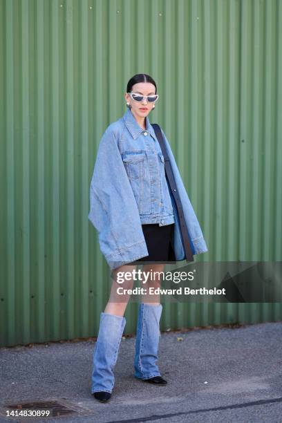 Guest wears silver sunglasses, a blue denim oversized jacket, a black short skirt, a blue denim large shoulder bag black suede pointed toe cap with...