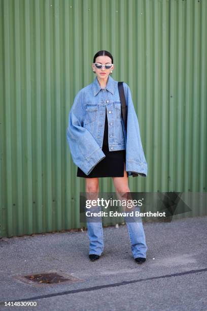 Guest wears silver sunglasses, a blue denim oversized jacket, a black short skirt, a blue denim large shoulder bag black suede pointed toe cap with...