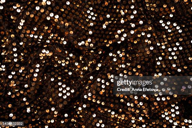 many golden sequins on black velvet. fragment of beautiful festive dress. close-up - jurk met lovertjes stockfoto's en -beelden