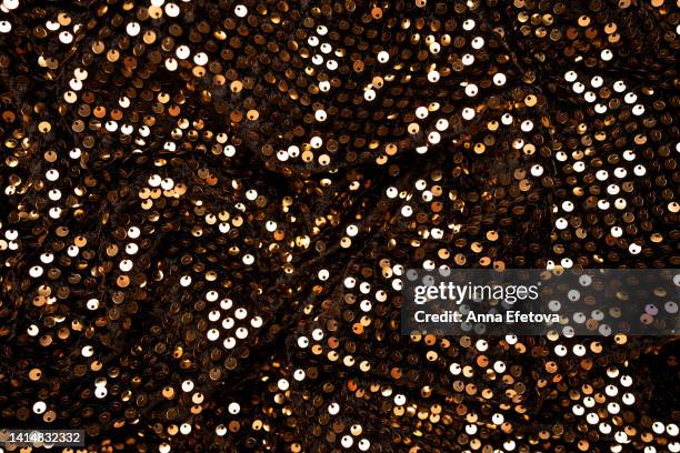 many golden sequins on black velvet. fragment of beautiful festive dress. close-up - gold dress stockfoto's en -beelden