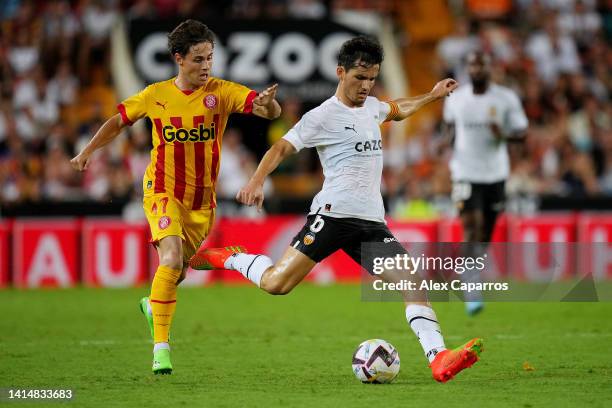 Hugo Guillamon of Valencia CF is challenged by Rodrigo Riquelme of Girona FC during the LaLiga Santander match between Valencia CF and Girona FC at...