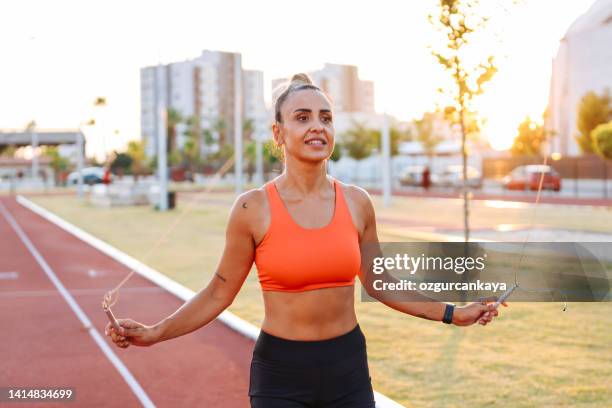 young woman with dreadlocks on her head jumping rope in the park. healthy lifestyle. - skip stockfoto's en -beelden