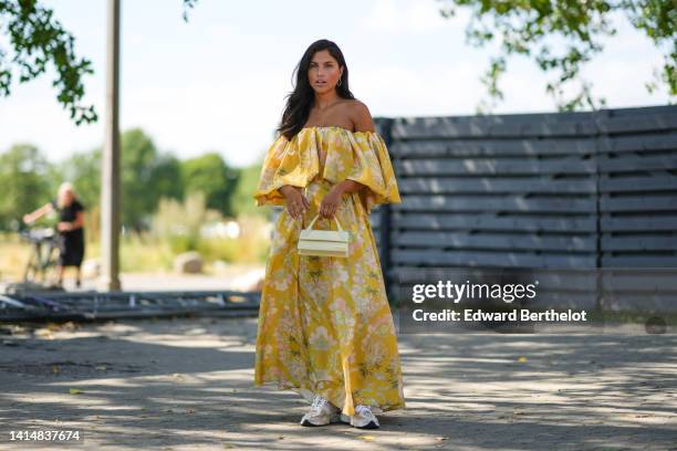 Guest wears gold earrings, a yellow with green / pink flower print pattern shoulder-off / ruffled long dress, a pale yellow matte leather Baguette...