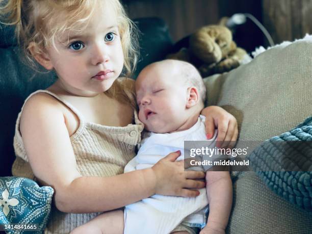 toddler girl with her baby sibling - changing form stock pictures, royalty-free photos & images