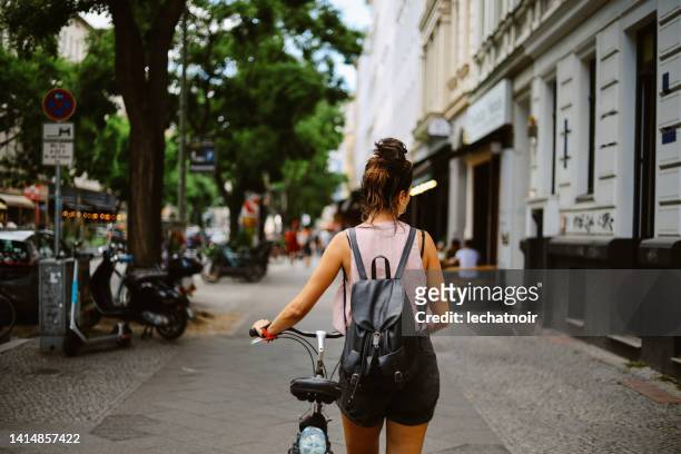 woman pushing her bicycle on the streets of berlin - kreuzberg stock pictures, royalty-free photos & images