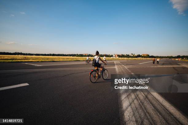 woman riding her bicycle in tempelhof, berlin - tempelhof stock pictures, royalty-free photos & images