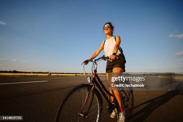 woman riding her bicycle in tempelhof, berlin - tempelhof airport stock pictures, royalty-free photos & images