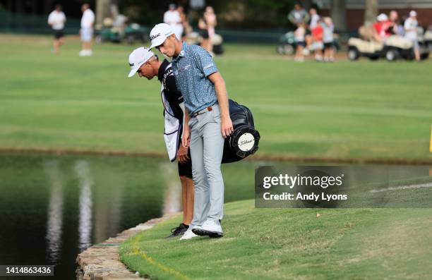 Will Zalatoris of the United States talks with his caddie on the third playoff hole on the 11th green after his ball went in the water during the...