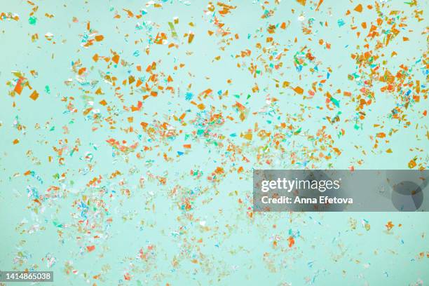 many orange foil confetti on light blue background. holiday backdrop. concept of new year coming party. flat lay style - confetti light blue background stock pictures, royalty-free photos & images