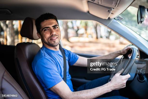 portrait of a mid adult man driving a car - uber driver stock pictures, royalty-free photos & images