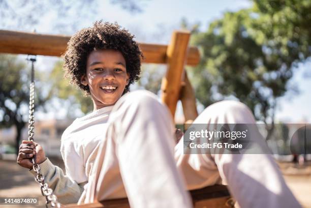 portrait of a happy boy playing in a swing - black boys stock pictures, royalty-free photos & images