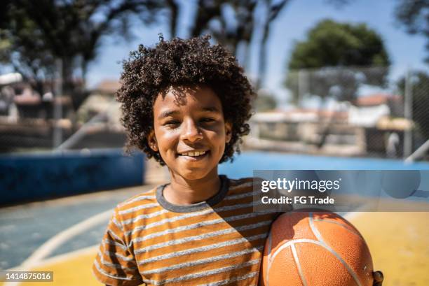 portrait of a boy holding a basketball ball at a sports court - vrijetijd sport en spel stockfoto's en -beelden