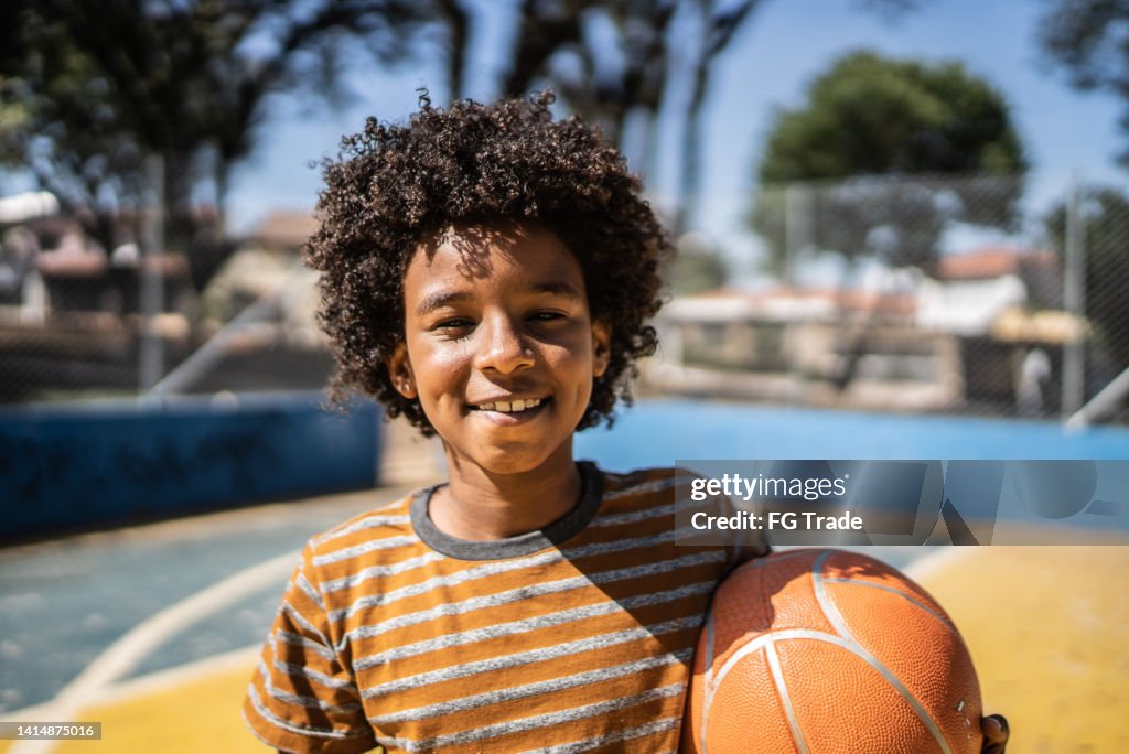 Portrait of a boy holding a basketball ball at a sports court