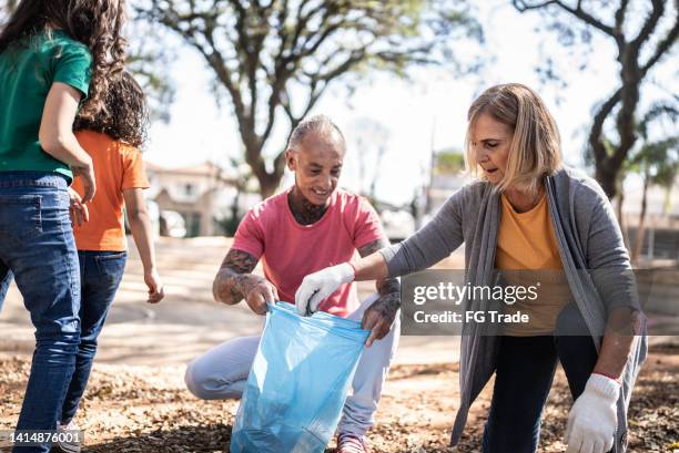 people picking up garbage to clean a public park - world humanitarian day stock pictures, royalty-free photos & images